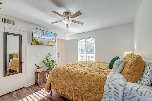 bedroom with a ceiling fan, visible vents, and wood finished floors