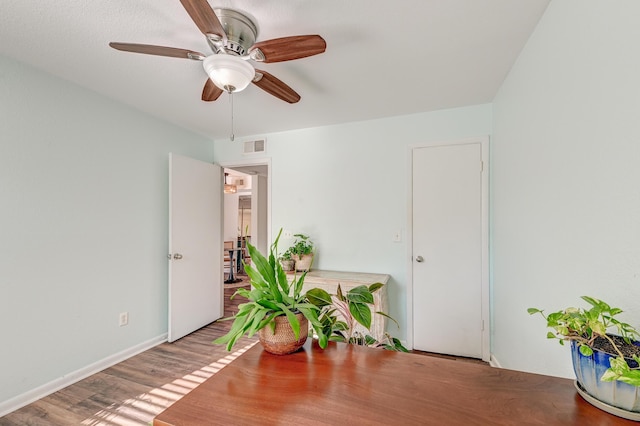 interior space featuring visible vents, ceiling fan, baseboards, and wood finished floors