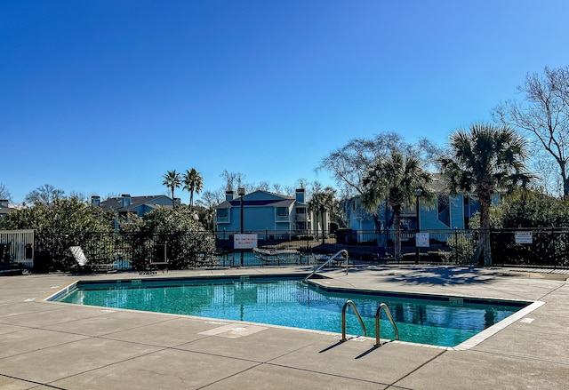 community pool with a patio area and fence