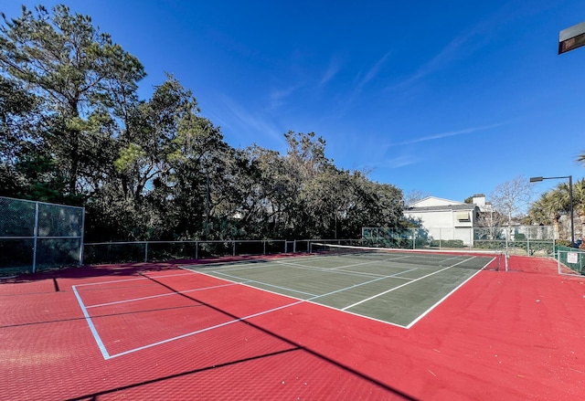 view of tennis court with community basketball court and fence