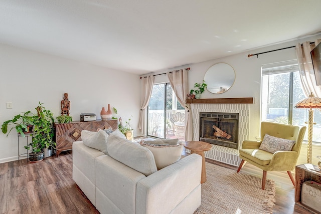 living area with a brick fireplace, baseboards, and wood finished floors