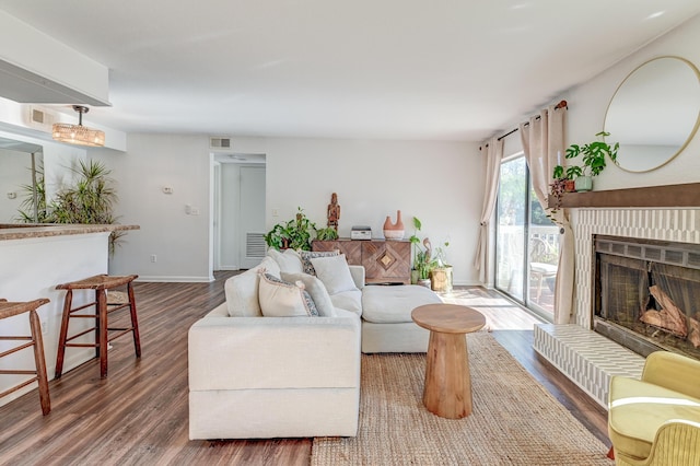 living room with baseboards, a fireplace, visible vents, and wood finished floors