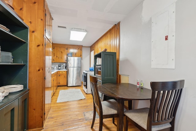 kitchen with gas range gas stove, stainless steel refrigerator, light hardwood / wood-style flooring, and electric panel