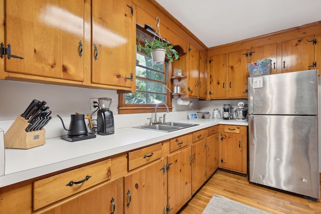 kitchen with sink, stainless steel fridge, and light hardwood / wood-style flooring