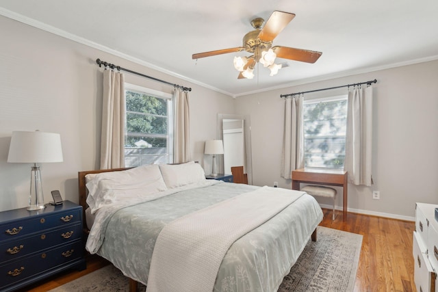 bedroom featuring ceiling fan, multiple windows, light hardwood / wood-style flooring, and crown molding