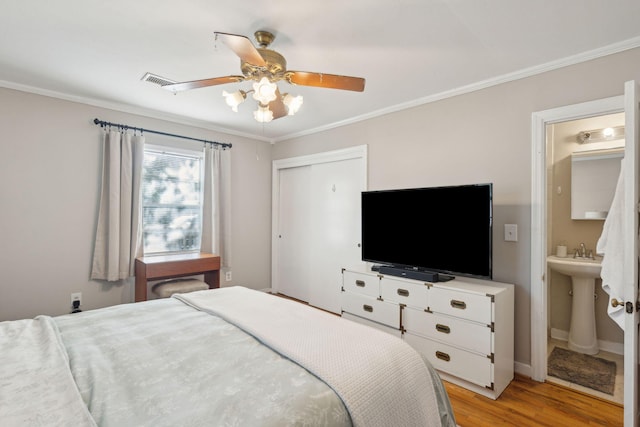 bedroom featuring a closet, ceiling fan, ensuite bathroom, light hardwood / wood-style flooring, and crown molding