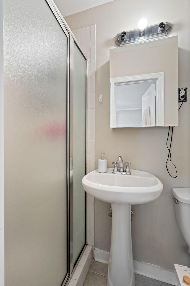 bathroom with walk in shower, sink, tile patterned flooring, and toilet