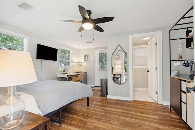 bedroom with ceiling fan, hardwood / wood-style flooring, multiple windows, and ensuite bathroom