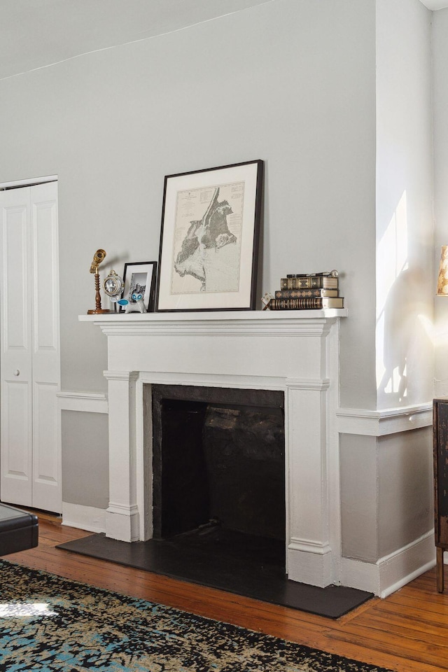 interior details with a fireplace with raised hearth, wood finished floors, and baseboards