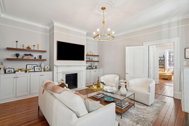 living room featuring dark wood-style floors, ornamental molding, a fireplace with flush hearth, and an inviting chandelier