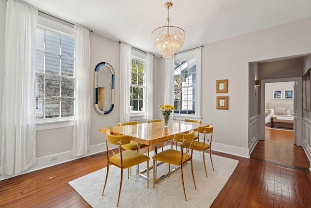 dining area featuring a notable chandelier, wood-type flooring, visible vents, and baseboards