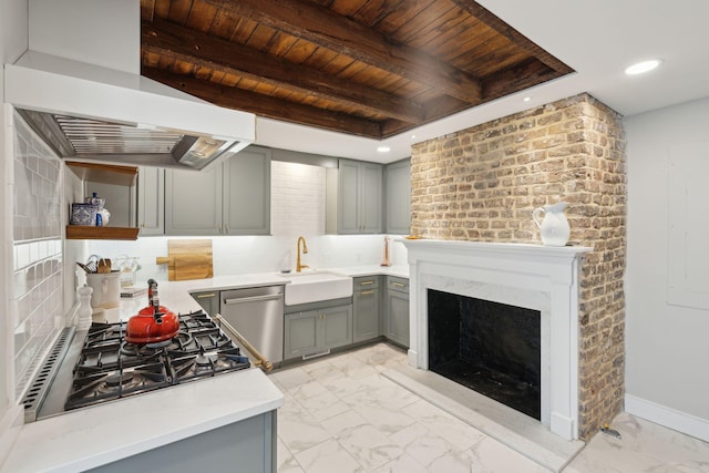 kitchen featuring wall chimney exhaust hood, a sink, marble finish floor, light countertops, and stainless steel dishwasher