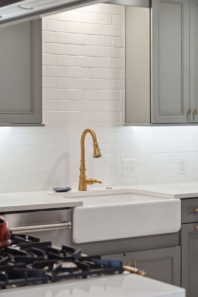 interior details with tasteful backsplash, light countertops, and gray cabinetry