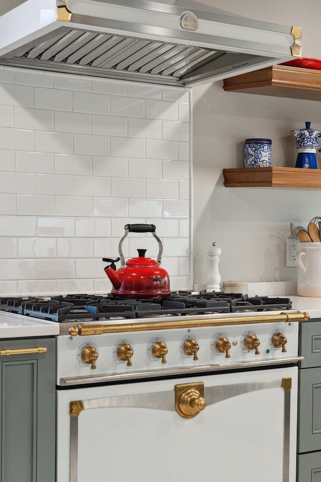 kitchen featuring range, wall chimney exhaust hood, tasteful backsplash, and light countertops