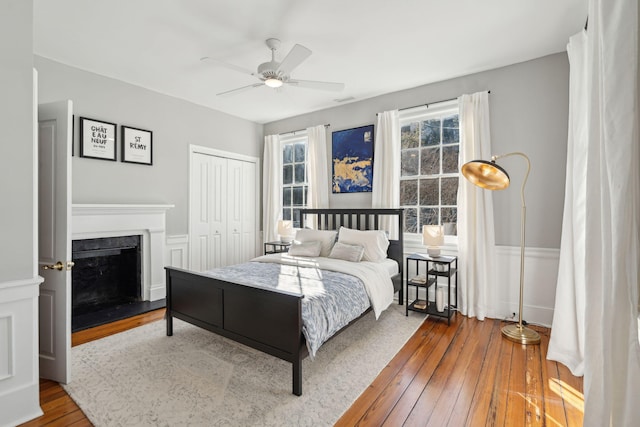 bedroom with a wainscoted wall, a closet, a fireplace, and hardwood / wood-style floors