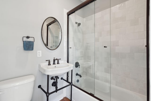 bathroom with combined bath / shower with glass door and toilet