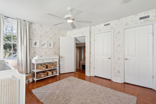 bedroom featuring baseboards, wood finished floors, visible vents, and wallpapered walls