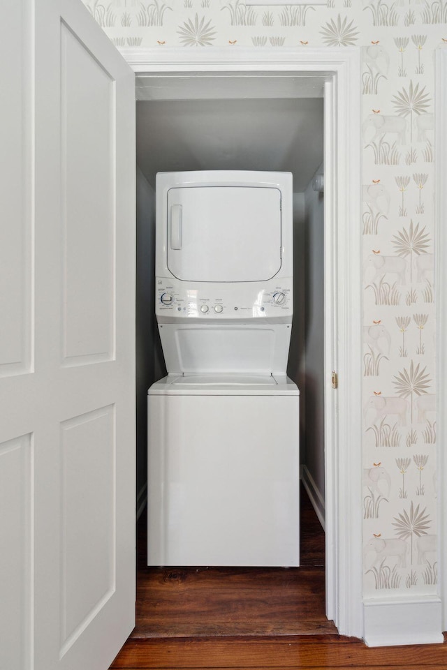 laundry room featuring baseboards, laundry area, stacked washer and clothes dryer, and wallpapered walls