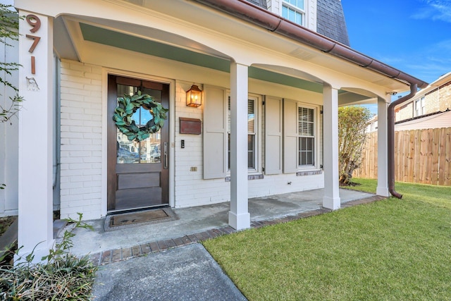 view of exterior entry featuring a yard and covered porch