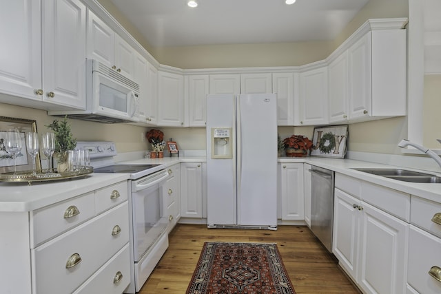 kitchen with sink, white cabinets, wood-type flooring, and white appliances