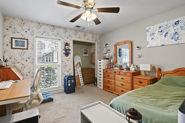 bedroom with wallpapered walls, a ceiling fan, visible vents, and light carpet