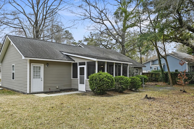 rear view of house featuring a sunroom, fence, a yard, and roof with shingles