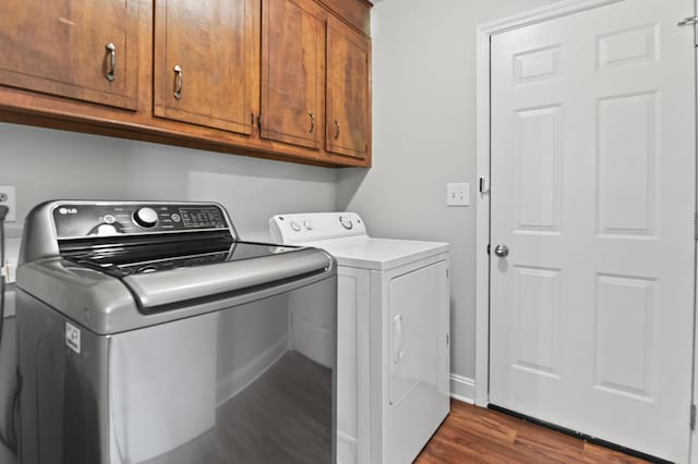 laundry area with washer and clothes dryer, cabinet space, dark wood finished floors, and baseboards