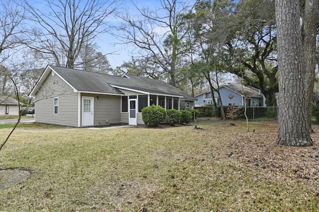 back of house with a sunroom, a lawn, a shingled roof, and fence