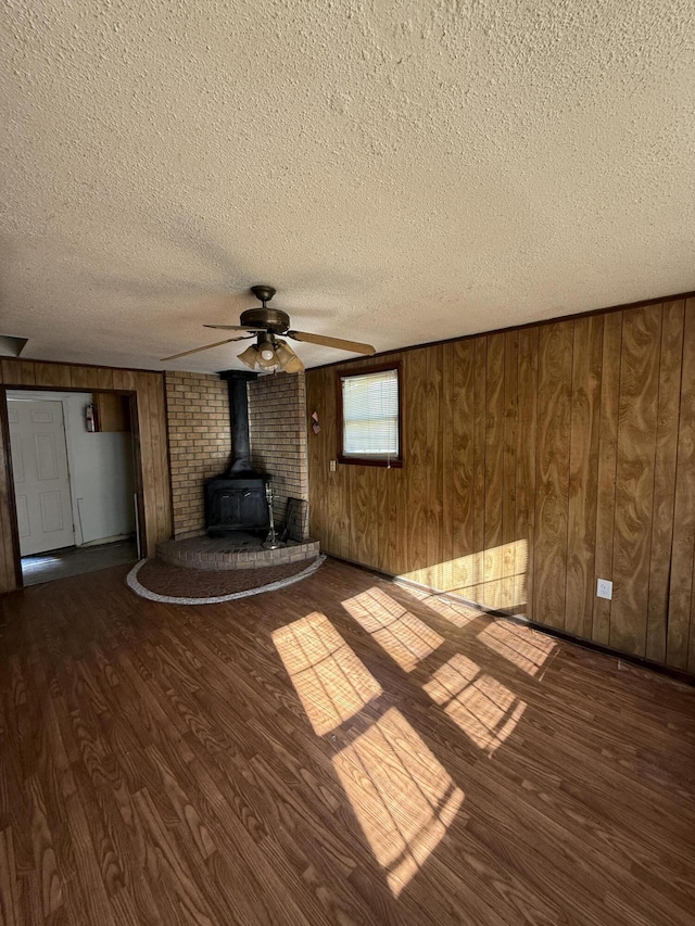 unfurnished living room with a textured ceiling, wood finished floors, and a wood stove