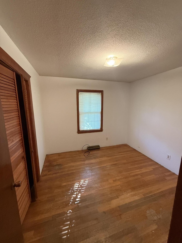 unfurnished bedroom featuring a textured ceiling, wood finished floors, and a closet
