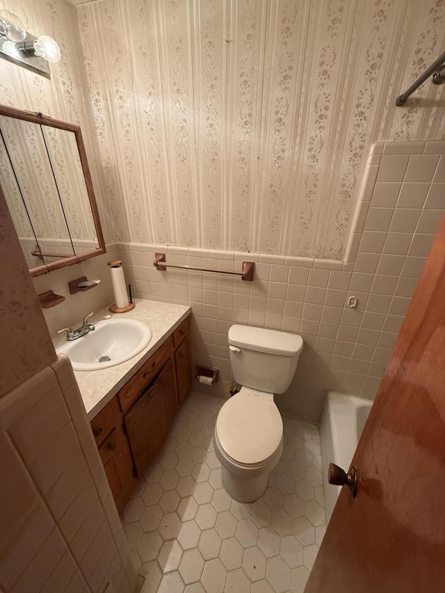 full bathroom featuring toilet, wallpapered walls, tile patterned flooring, and a wainscoted wall