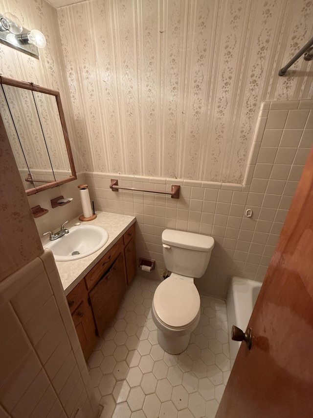full bathroom with vanity, toilet, tile patterned floors, a wainscoted wall, and wallpapered walls