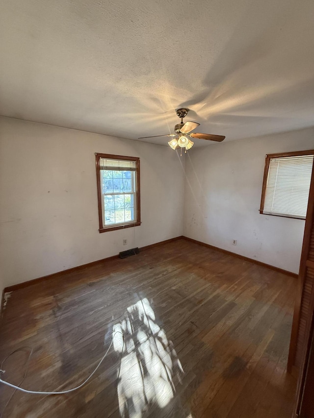 spare room with a ceiling fan, baseboards, wood finished floors, and a textured ceiling