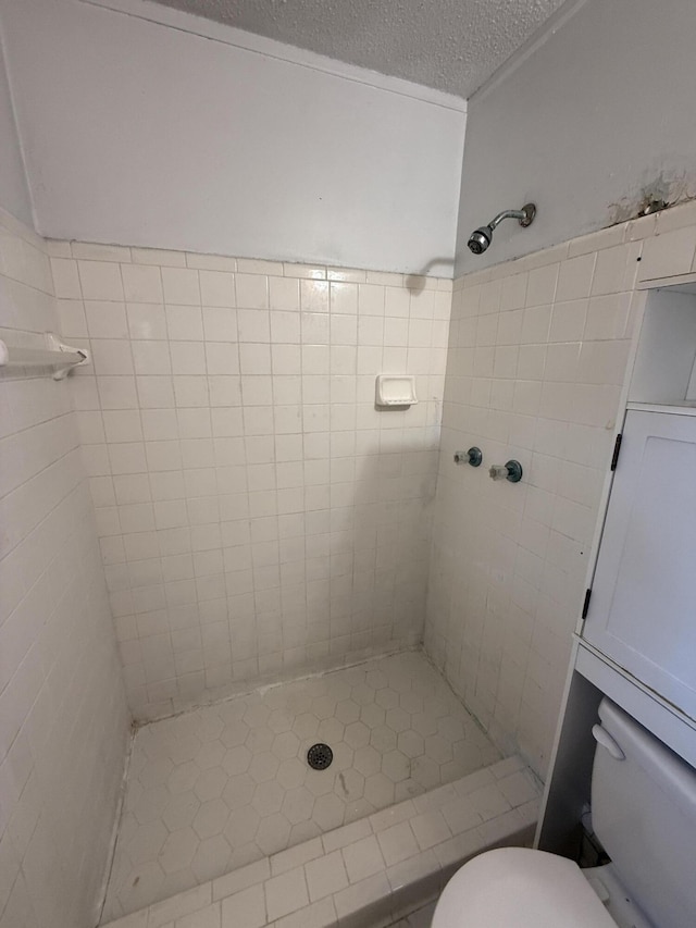full bath featuring tile patterned flooring, a textured ceiling, toilet, and a shower stall