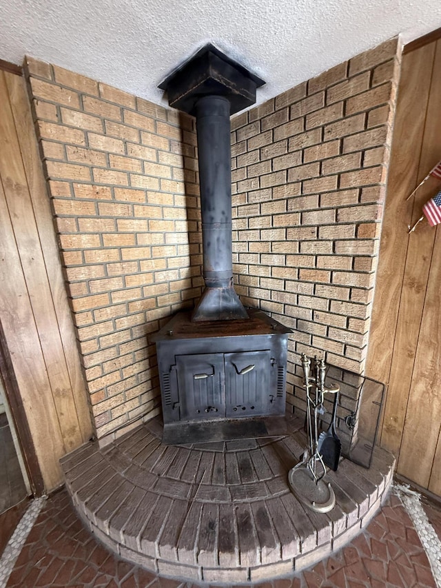 details with a textured ceiling, wood walls, and a wood stove