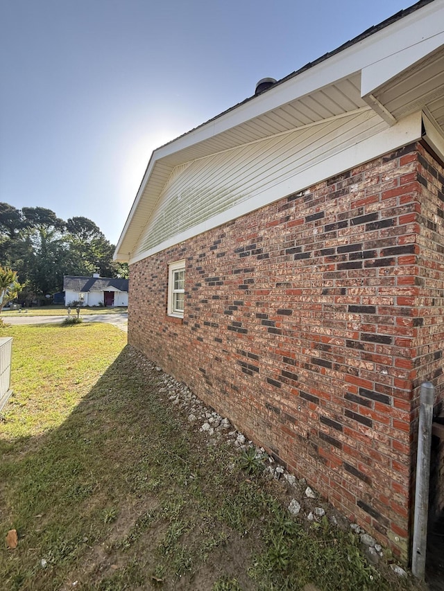 view of home's exterior featuring brick siding and a yard