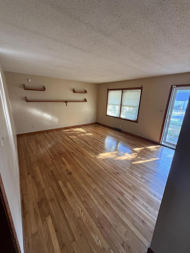 unfurnished living room featuring a textured ceiling, a healthy amount of sunlight, and wood finished floors