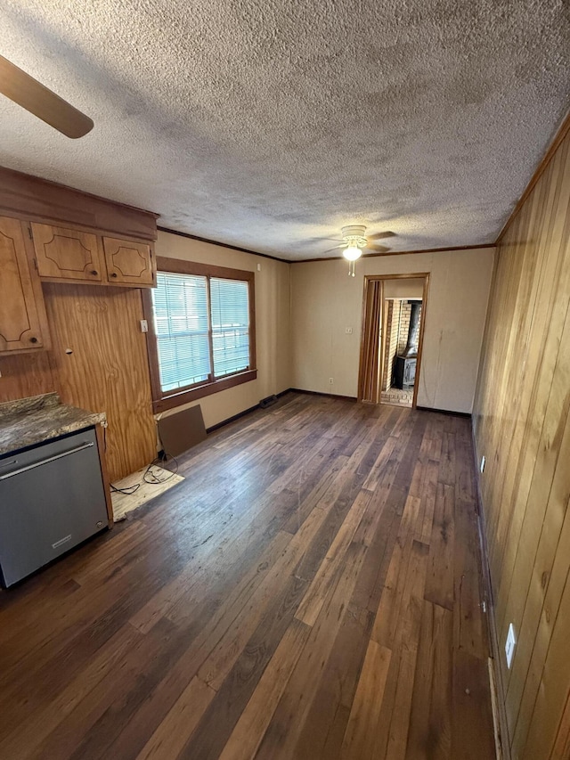 unfurnished living room with a ceiling fan, a textured ceiling, dark wood-style floors, and wood walls