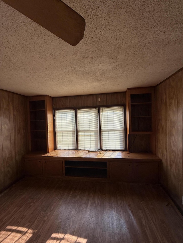 unfurnished room featuring a textured ceiling, wood walls, and wood finished floors