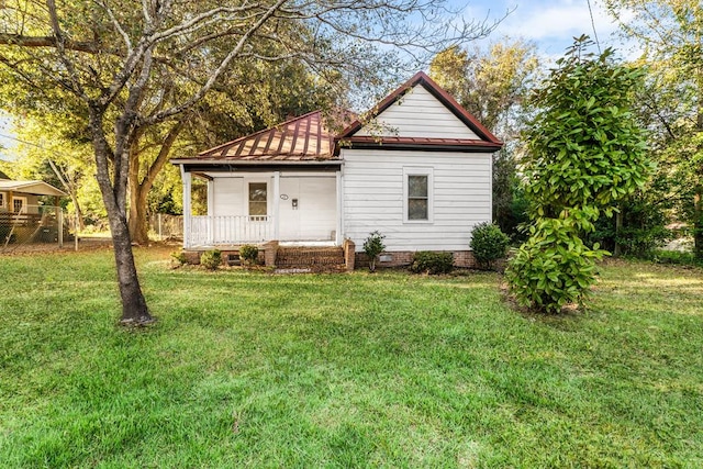 rear view of property featuring a yard and covered porch