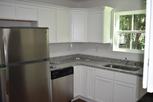 kitchen with light stone counters, sink, white cabinets, and appliances with stainless steel finishes