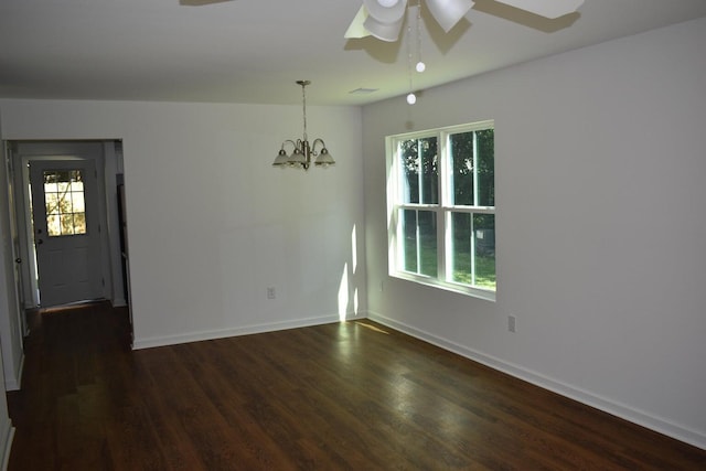 empty room featuring ceiling fan with notable chandelier and dark hardwood / wood-style floors