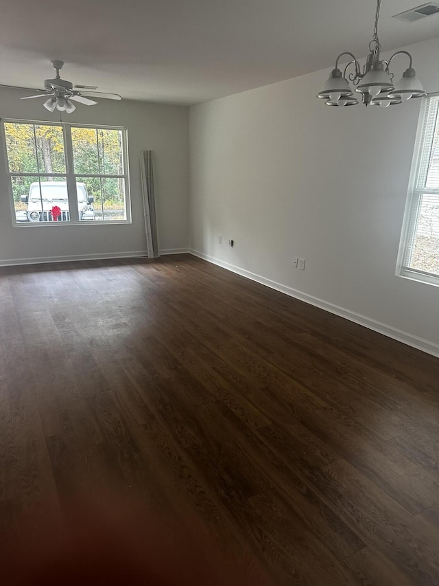 spare room with dark hardwood / wood-style floors, a healthy amount of sunlight, and ceiling fan with notable chandelier