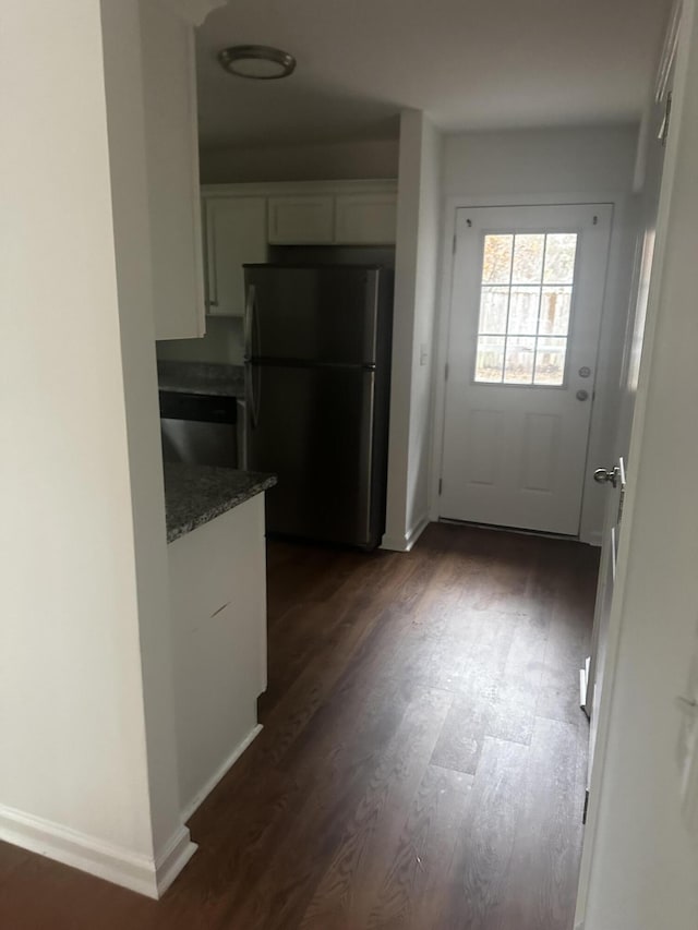 kitchen with stainless steel fridge, dark hardwood / wood-style flooring, white cabinets, and dark stone counters