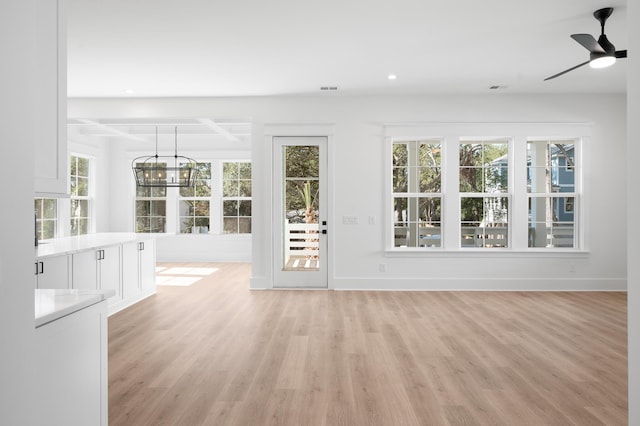 interior space featuring ceiling fan with notable chandelier, a wealth of natural light, and light hardwood / wood-style floors