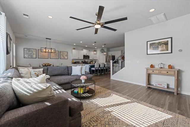 living room with dark wood-type flooring and ceiling fan with notable chandelier