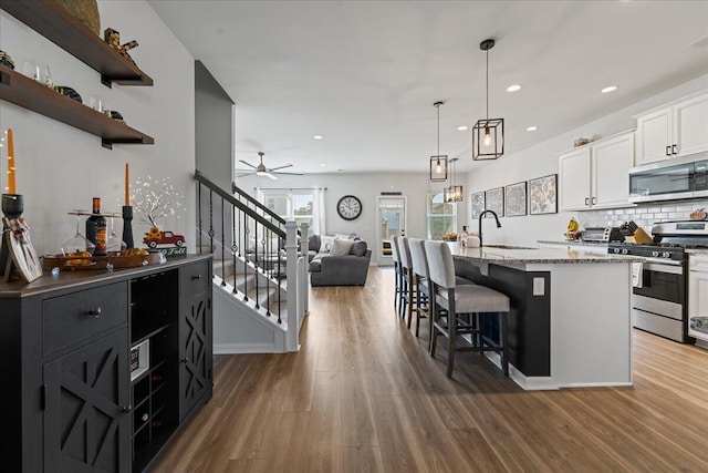 kitchen with appliances with stainless steel finishes, decorative light fixtures, white cabinetry, sink, and a kitchen bar