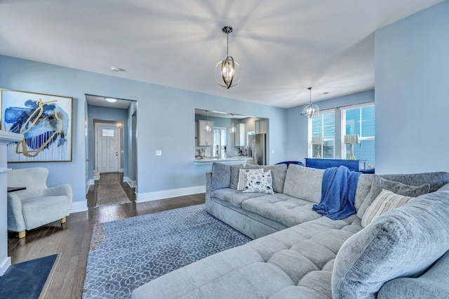 living room with dark wood-style floors, a chandelier, and baseboards