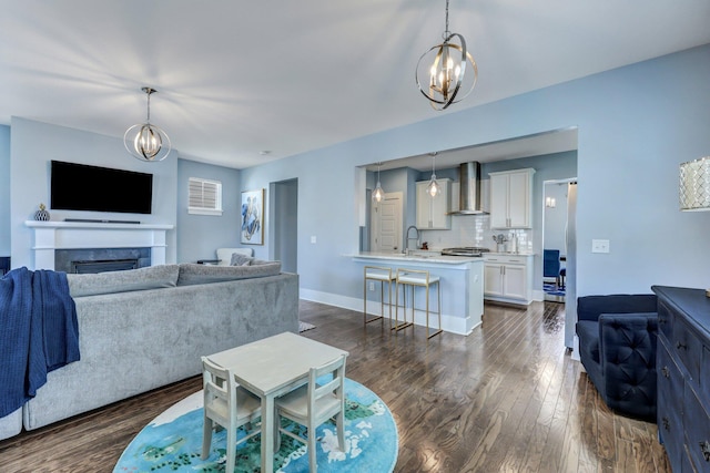 living area with dark wood-style floors, a fireplace, baseboards, and an inviting chandelier