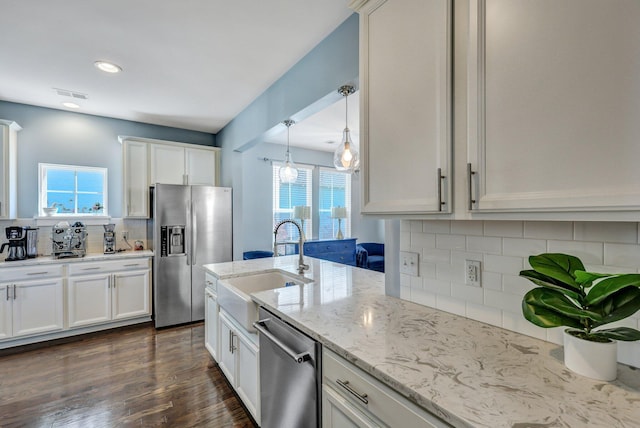 kitchen featuring light stone countertops, a sink, stainless steel appliances, dark wood-type flooring, and white cabinetry